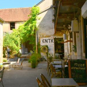 an outdoor patio with tables and chairs and a restaurant at Au Canari gîte de charme in Saint-Sauveur-en-Puisaye