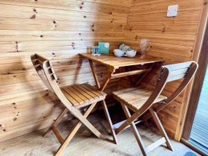a wooden table and two chairs in a room at Chestnut Meadow Camping & Glamping in Sidley