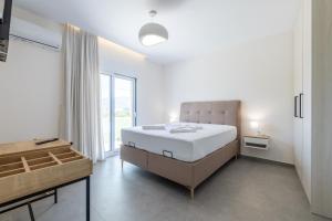 a white bedroom with a large bed and a window at Enclave Luxury Apartments in Áyios Kírikos +124 photos