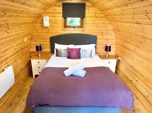 a bedroom with a large bed in a wooden cabin at Chestnut Meadow Camping & Glamping in Sidley