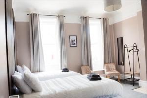 a bedroom with two white beds and two windows at Ship Inn in Wylam
