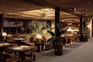 a restaurant with tables and chairs and potted plants at Twinpalms Treehouses Phuket in Bang Tao Beach