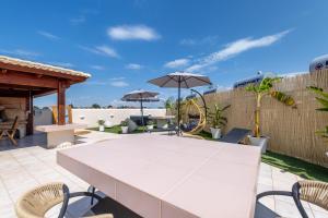 a patio with a table and chairs and umbrellas at Enclave Luxury Apartments in Áyios Kírikos