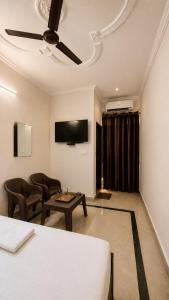 a room with a bed and a table and a tv at Wama Rooms in New Delhi