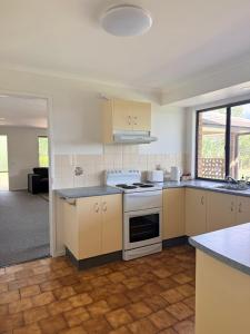 a kitchen with white cabinets and a stove top oven at Valley View House in Gympie