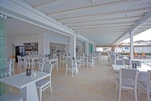a restaurant with white tables and white chairs at Yiannaki Hotel in Ornos