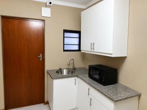 a small kitchen with a sink and a microwave at Springforth Guesthouse in De Grendel