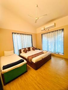 a bedroom with two beds and a ceiling fan at Amrapali Villa at Raghunandan Resort in Nashik