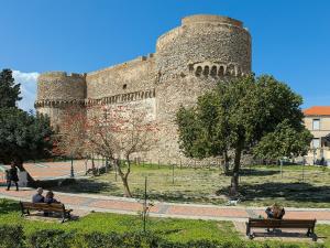 a group of people sitting on benches in front of a castle at Alba Mediterranea in Reggio di Calabria