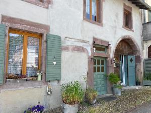 a building with a green door and windows and plants at Le temps d'une pause bed and breakfast in Servance