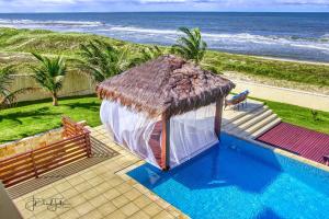 a small hut with a thatched roof next to the ocean at Casa da Estrela in Barra do Cunhau