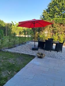 a patio with a table and a red umbrella at Maison entière in Dax