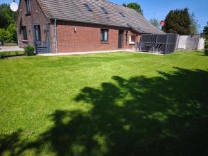 a house with a green yard with a large lawn at Haus am Deich in Norden