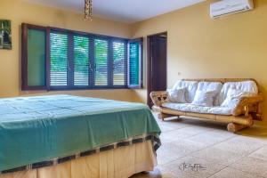 a bedroom with a bed and a couch and windows at Casa da Estrela in Barra do Cunhau +47 photos
