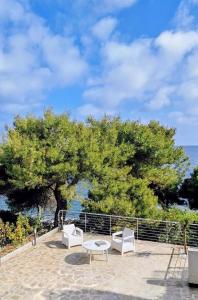 a group of white chairs and a table and a tree at Minnelea Blue Retreat in Acciaroli