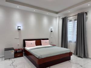 ein Schlafzimmer mit einem Bett mit rosa Kissen und einem Fenster in der Unterkunft Charnel hosting in Kribi + 24 Fotos