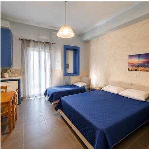 a bedroom with two beds and a table and a kitchen at Zannikos Rooms in Ermoupoli