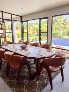 a dining room with a table and chairs and windows at Sikeci Villa in Pacific Harbour