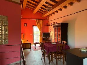 a kitchen with a table and a dining room with red walls at Appartamento Villa Reale in Castel SantʼAngelo