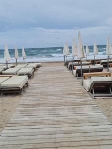 a wooden boardwalk with chairs and umbrellas on the beach at Le cocon Sétois - T2 et garage privé in Sète