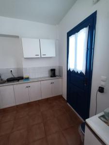 a kitchen with a blue door and white cabinets at Evdokia3 in Koufonisia +10 photos