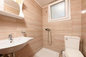 a bathroom with a sink and a toilet and a window at Qyra Studios in Skala Rachoniou