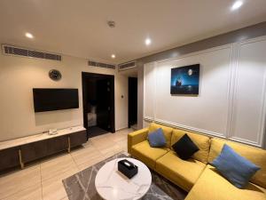 a living room with a yellow couch and a tv at Art Suite in Riyadh