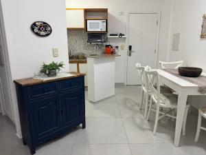 a kitchen with a blue cabinet and a table at Flat lindo a 120 metros da praia de Riviera de São Lourenço até 4 pessoas in Bertioga