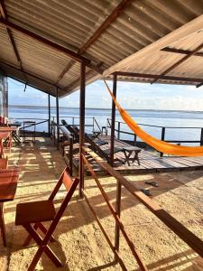 a deck with chairs and a hammock on the beach at Chalé Mar Aberto in Atins