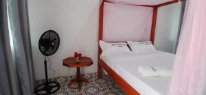 a room with two beds and a fan and a table at Ngalula Half London Resort in Dzitsuhe