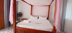 a bedroom with a four poster bed with a clock on the wall at Ngalula Half London Resort in Dzitsuhe +22 photos