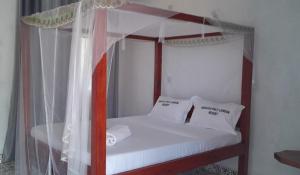 a bedroom with a canopy bed with white sheets and pillows at Ngalula Half London Resort in Dzitsuhe