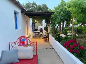 a red bench sitting outside of a house with flowers at Bombom Comporta in Melides