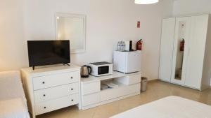 a white dresser with a tv and a microwave at Casa Nuno in Lagoa