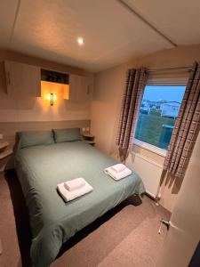 a bedroom with a bed with two towels on it at Tattershall Caravan- 28 The Pastures in Tattershall +14 photos