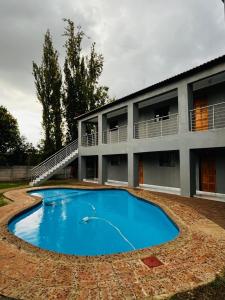 a house with a large blue pool in front of it at Rest Easy Guest House Pty Ltd Unit 5 in Boksburg