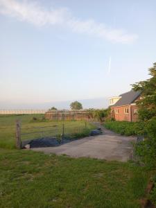 a driveway in a field with a house and a fence at B&B De koekoeksklok in IJsselmuiden +8 photos