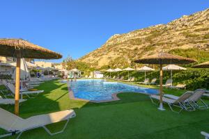 ein Pool mit Stühlen und Sonnenschirmen und ein Berg in der Unterkunft Fragiskos Hotel in Matala