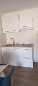 a kitchen with white cabinets and a sink at Le cocon Sétois - T2 et garage privé in Sète