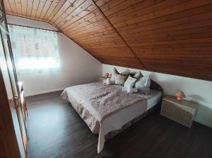 a bedroom with a bed and a wooden ceiling at Csengi Apartman in Balatonszárszó