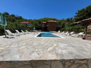 a swimming pool with lounge chairs and a group ofitures at Къща "Конакъ" in Ussoika