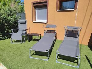 three lawn chairs sitting on the grass next to a building at Csengi Apartman in Balatonszárszó