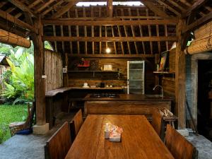 an outdoor kitchen with a wooden table and benches at The Payung House - Romantic Riverside Villa in Bebandem