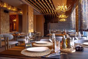 a dining room with tables and chairs and chandeliers at Apart-hotel Pahulja in Jahorina