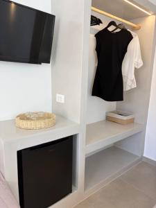 a living room with a tv and a shelf with a shirt and ahibition at The Dream in Ios Chora
