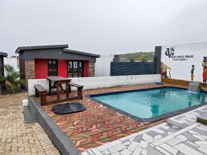 a swimming pool with a table and a bench next to a building at Vegas guest house in Dwarsloop