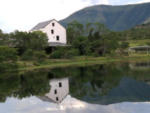 a reflection of a white barn in a lake at Glen Avon Farm in Somerset East