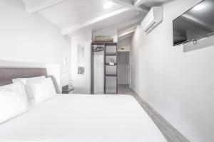 a white bedroom with a bed and a tv at Rua Grande Hotel in Viana do Castelo