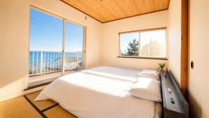 a bedroom with a large bed and a large window at SORA Blue House, 海辺の隠れ家, ペットBBQ可, 全3寝室&リビングオーシャンビュー,一棟貸切 in Hokota