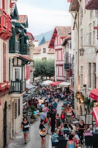 a group of people walking down a street with buildings at Etxe Ttippi in Saint-Jean-de-Luz